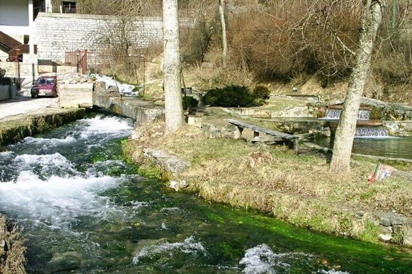 A river flowing through a park with benches and trees. 2