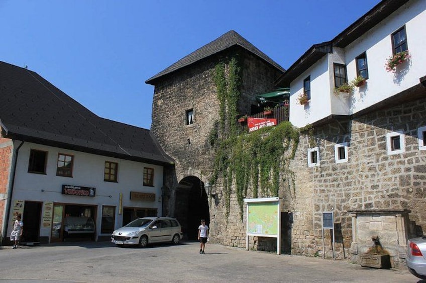 A stone building with a white facade, a car parked in front, and a clear blue sky. 3
