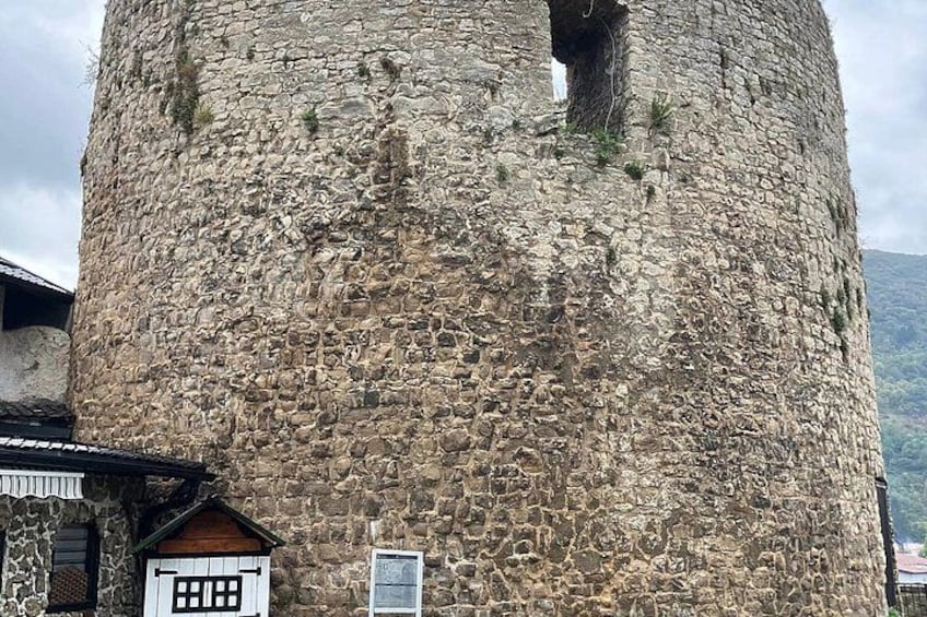 A stone tower with a large hole in the center, surrounded by buildings. 2