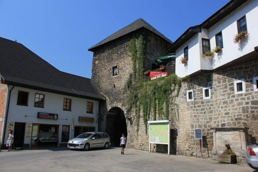 A stone building with a sign, a white building with a sign, and a car parked in front. 3