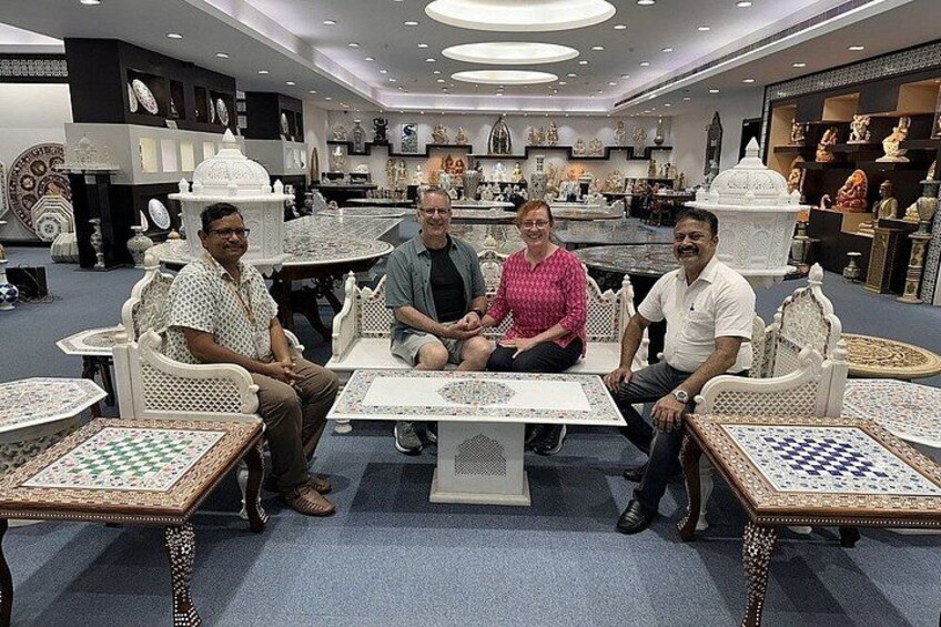 A group of people seated at tables with chessboards in a store with shelves of decorative items. 4