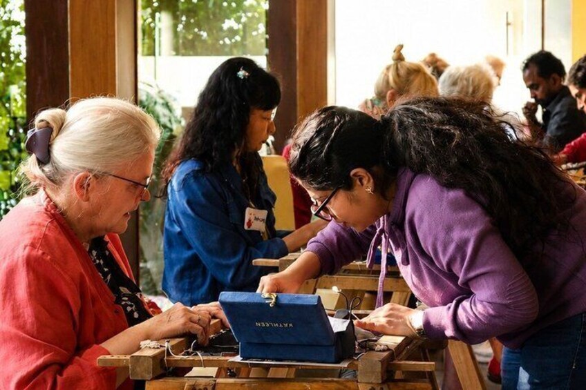 People engaged in a craft activity at a table with a laptop and wooden blocks. 1
