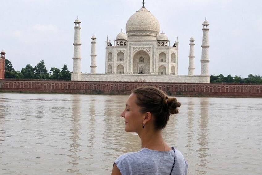 A person standing in front of the Taj Mahal with the river in the foreground. 2