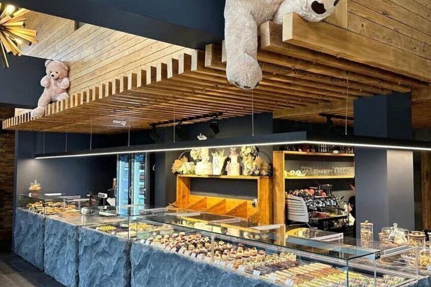 A bakery display with pastries and a teddy bear. 2