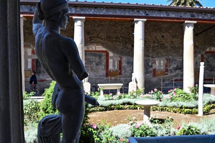 A classical statue in a garden with columns and a fountain. 5