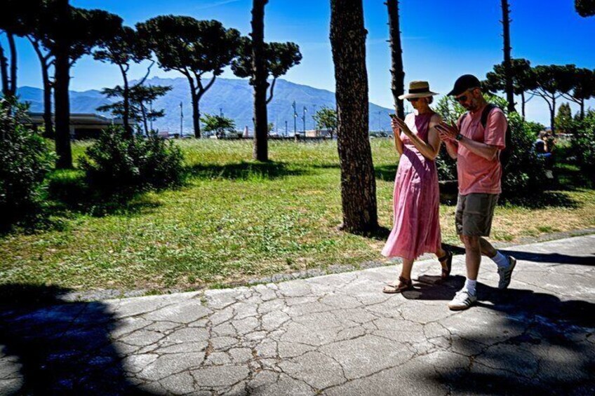 Two people walking on a stone path with trees and a mountain in the background. 2