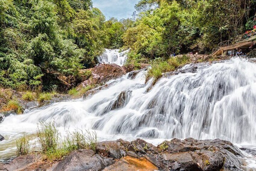 A waterfall cascading over rocks surrounded by dense green foliage. 4