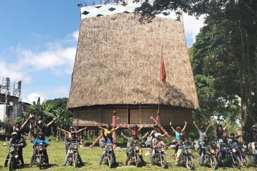 A group of people on motorcycles in front of a thatched-roof building. 3