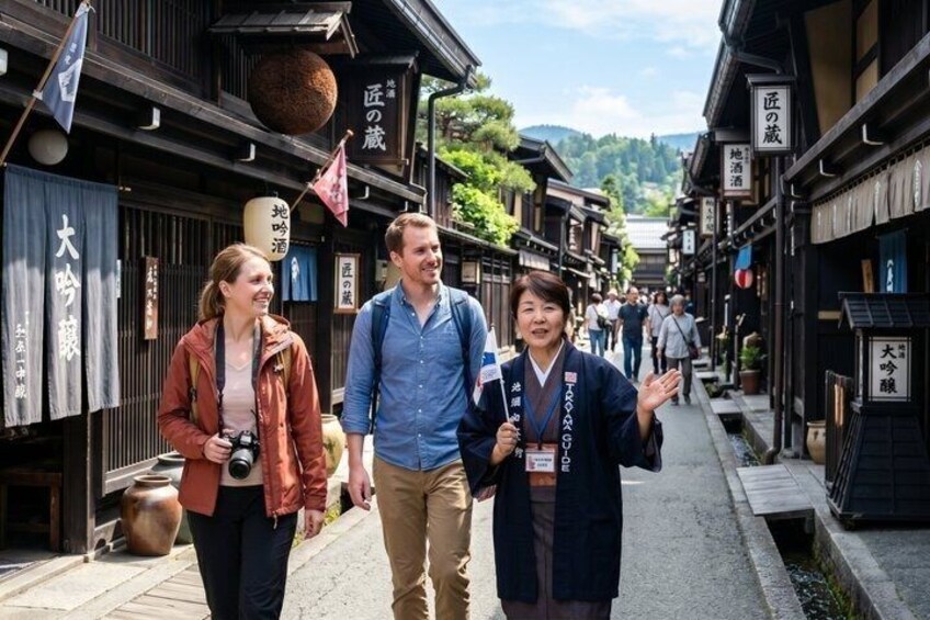 A narrow street lined with traditional wooden buildings, signs in Japanese, and a few people walking. 1