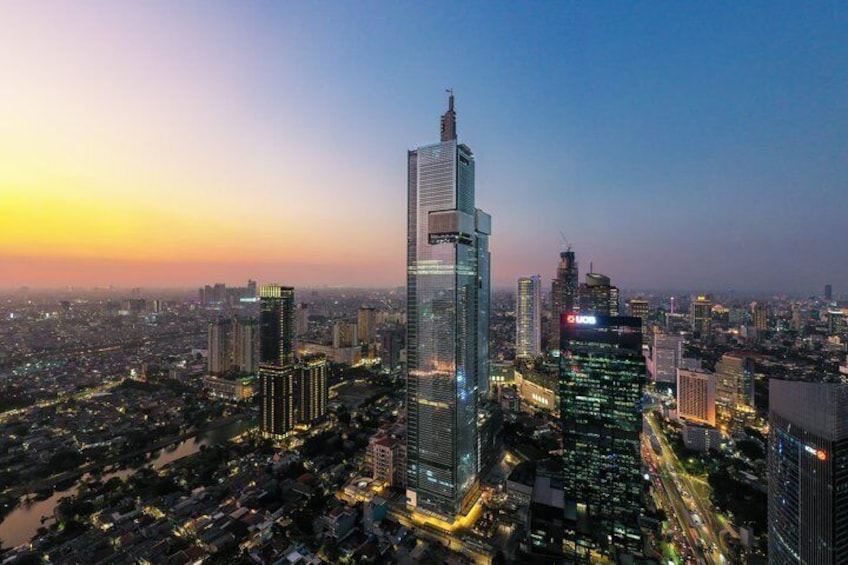 A cityscape at dusk with illuminated skyscrapers and a river. 1