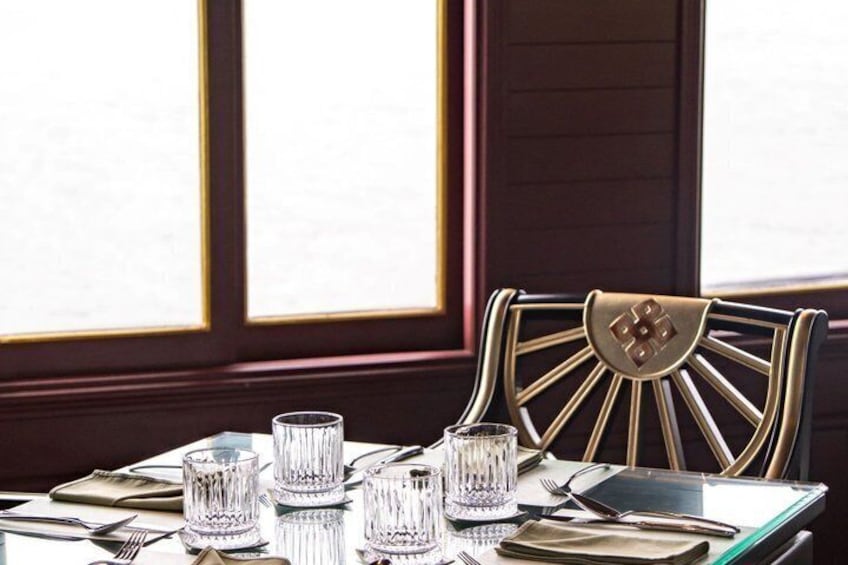 A dining table set with glassware and cutlery, a chair with a sunburst design, and a window with a view. 4