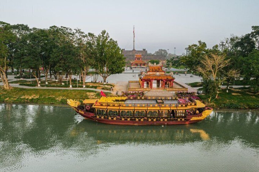 A traditional boat with ornate decorations on a calm river, surrounded by trees and a temple in the background. 2