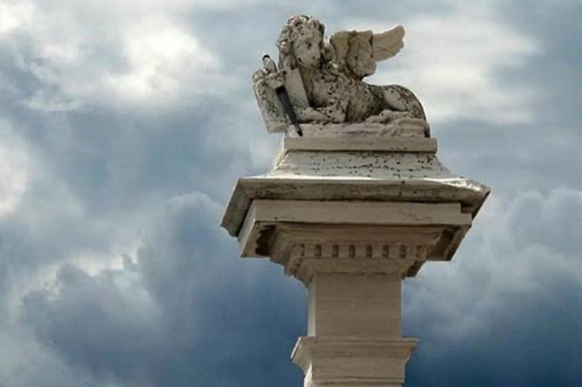 A stone statue of a lioness on a pedestal against a cloudy sky. 4