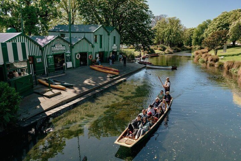 A rowboat with people, a dock, and a green building with a sign. 1