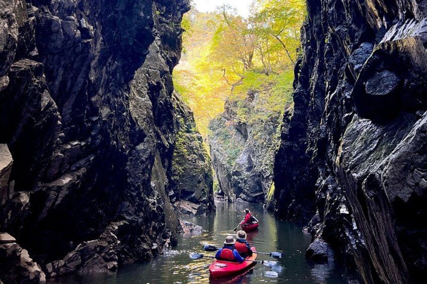 A narrow canyon with kayaks on a calm river. 3
