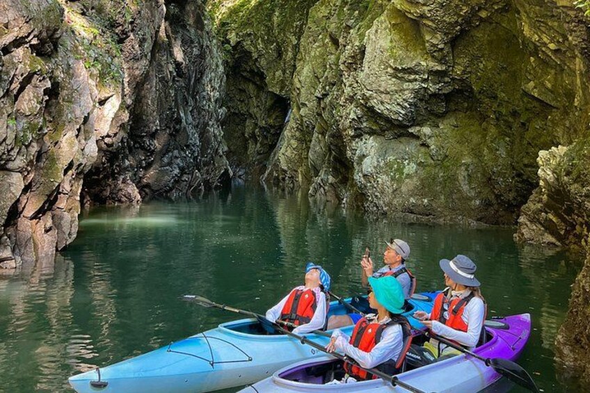 Three kayaks on a calm river surrounded by rocky cliffs. 2