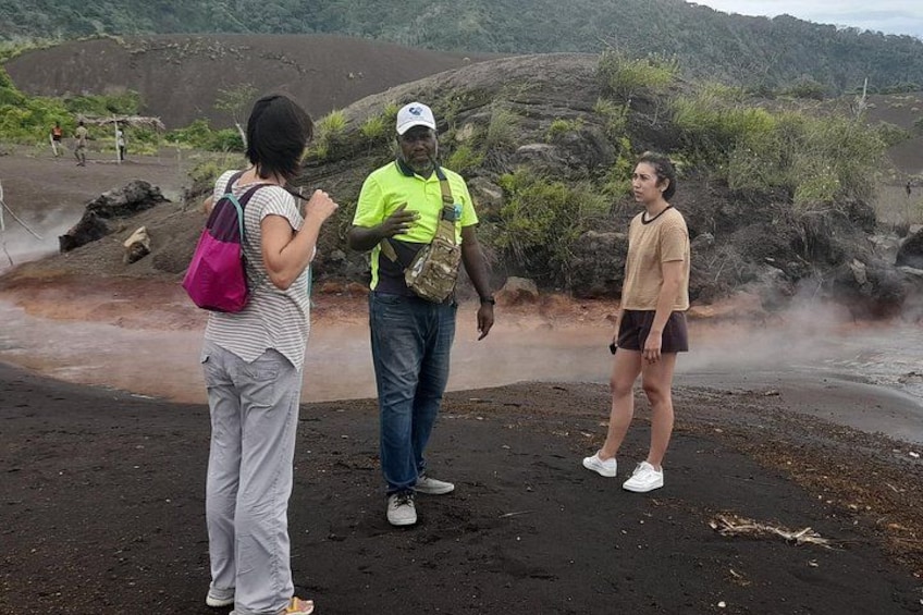 Three people standing on a volcanic landscape with steam rising from the ground. 1
