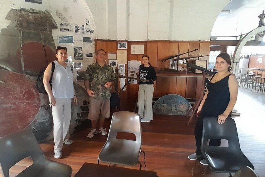 A group of people in an indoor setting with a large aircraft model, wooden paneling, and a counter. 3