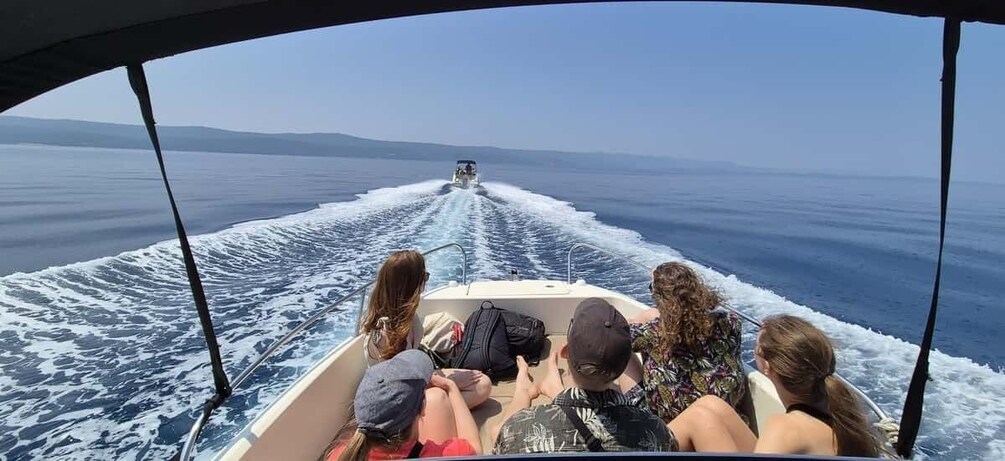 A boat with four people on board, moving on a body of water with a wake behind it. 4