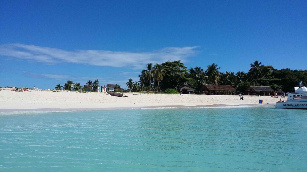 A beach with clear turquoise water, white sand, and palm trees. 5