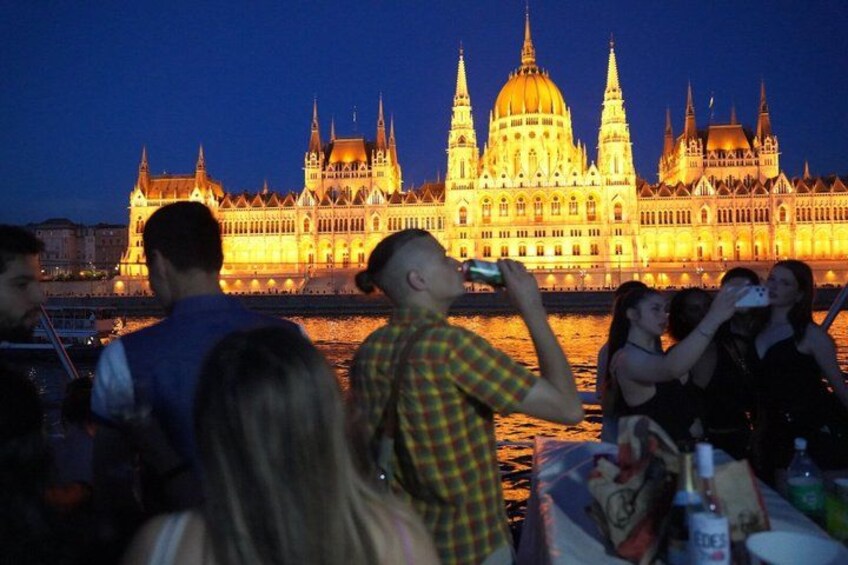 A group of people near a river with a large illuminated building in the background. 4