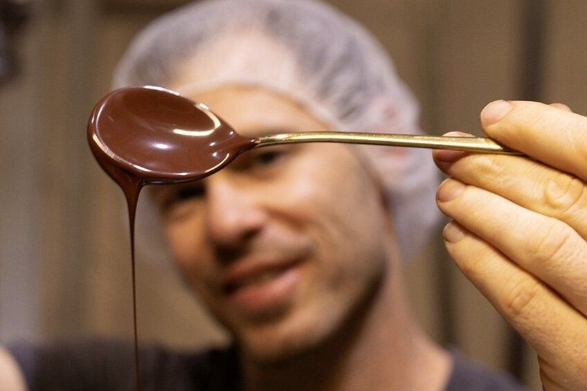 A person holding a spoon with chocolate melting on it. 5