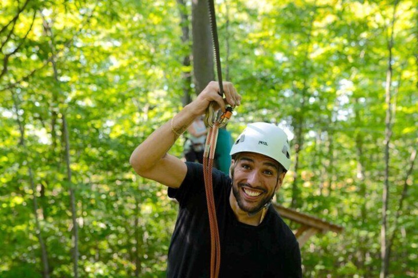 A person in a forest holding a zip line. 3