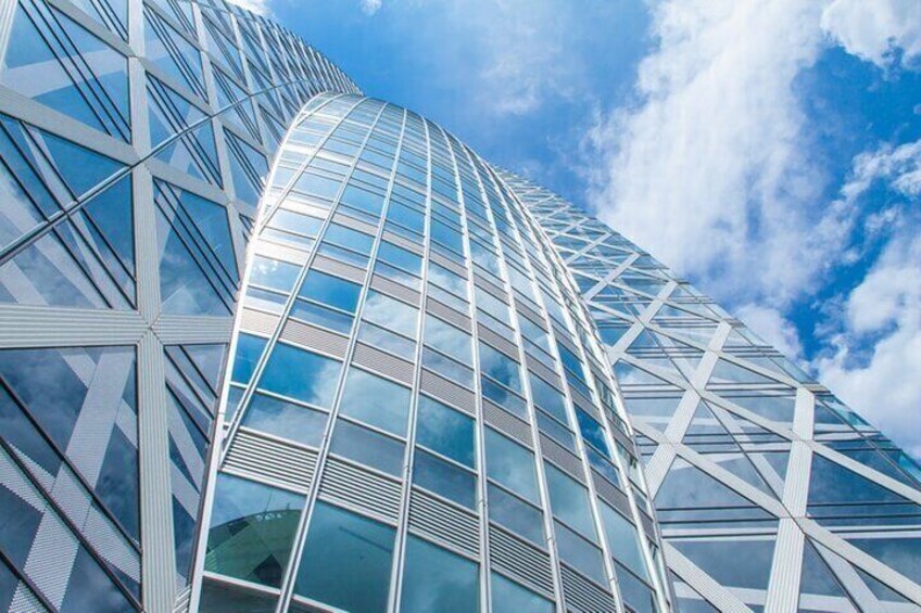 A modern glass skyscraper with a curved facade and a grid-like pattern of windows. 4
