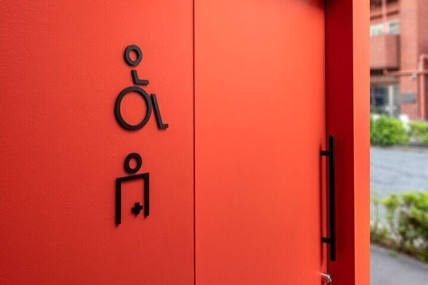 A red door with a wheelchair accessibility symbol and a person with a crutch symbol. 1