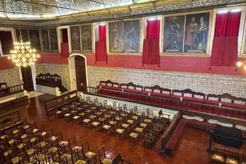 A grand hall with rows of chairs, a stage, and red curtains. 5
