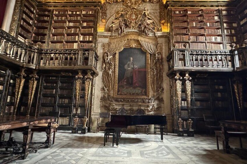 An ornate library with tall bookshelves, a central painting, and classical architecture. 1