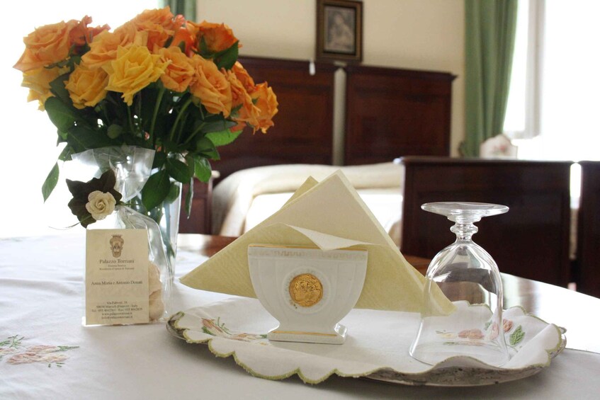 A table with a vase of roses, a napkin holder, a glass, and a nameplate. 2
