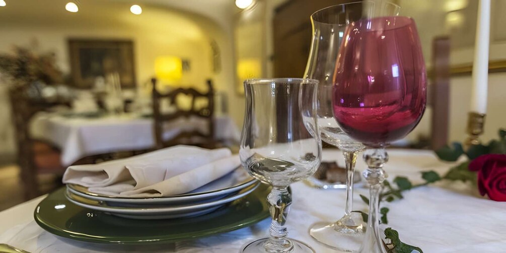 A dining table with plates, glasses, and a rose. 5