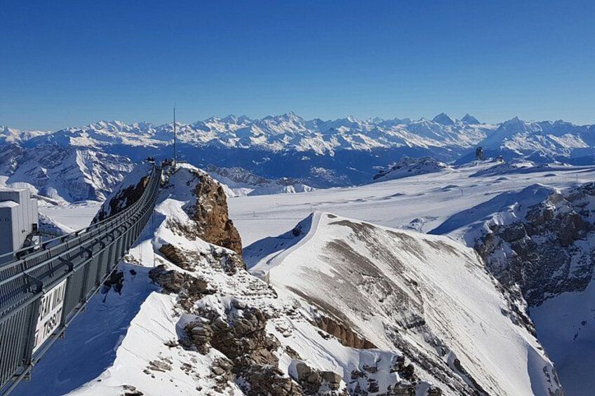 A snow-covered mountain landscape with a cable car system and distant snow-capped peaks. 4