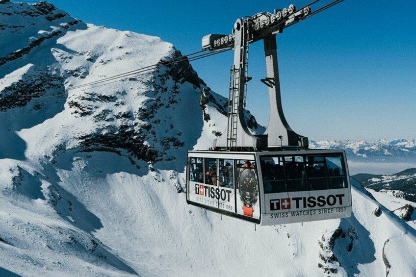 A Tissot branded cable car ascending a snowy mountain. 1