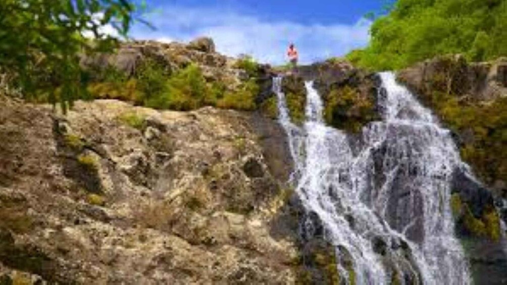 A waterfall cascading over rocks with greenery around. 4