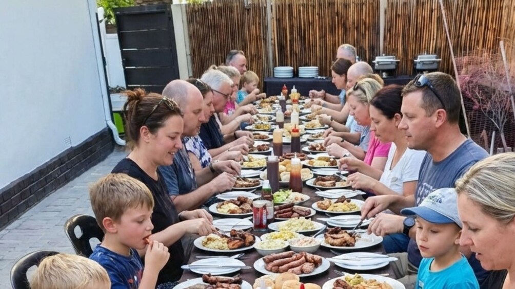 Un grupo de personas sentadas alrededor de una mesa larga, degustando diferentes platos. 3