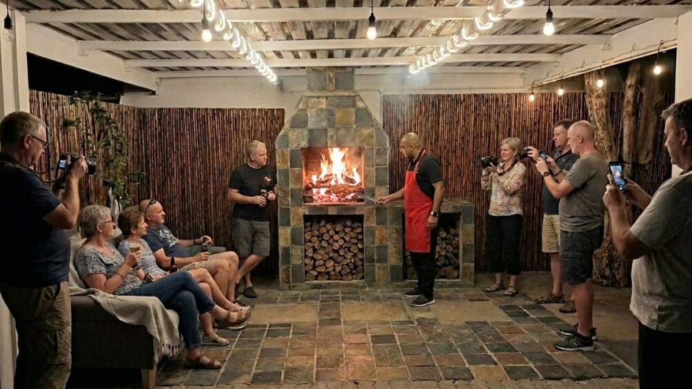 Un grupo de personas alrededor de una chimenea de piedra con fuego, algunas tomando fotografías. 5