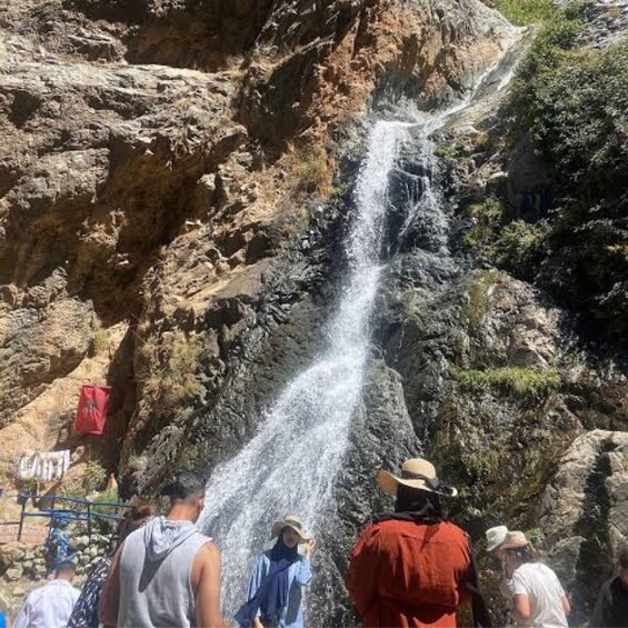 A waterfall cascading down a rocky cliff surrounded by visitors. 4