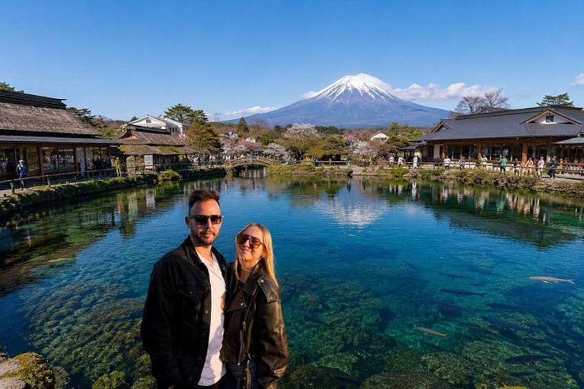 A couple standing by a clear lake with a mountain in the background. 2