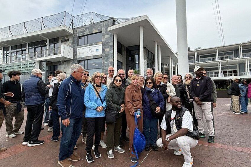 A group of people standing in front of a modern building with columns and a glass facade. 4