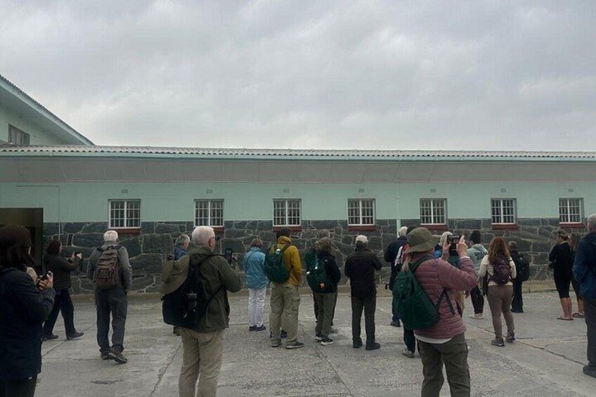 A group of people standing in a courtyard with a stone building in the background. 5