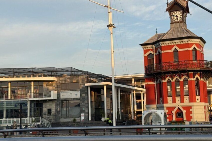 A waterfront building with a clock tower, a modern glass structure, and a red brick tower. 2