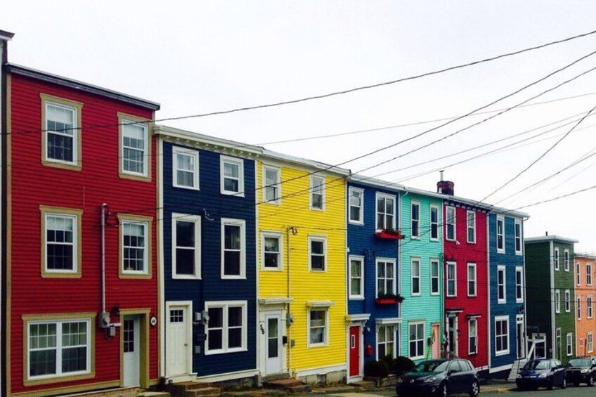A row of colorful row houses with cars parked in front. 4