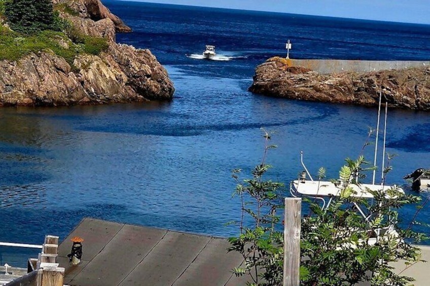 A rocky coastline with a boat in the water and a dock with a sailboat. 5