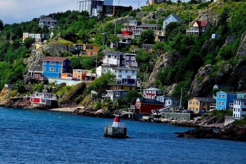 A coastal village with colorful houses on a hillside, a lighthouse, and a calm sea. 5