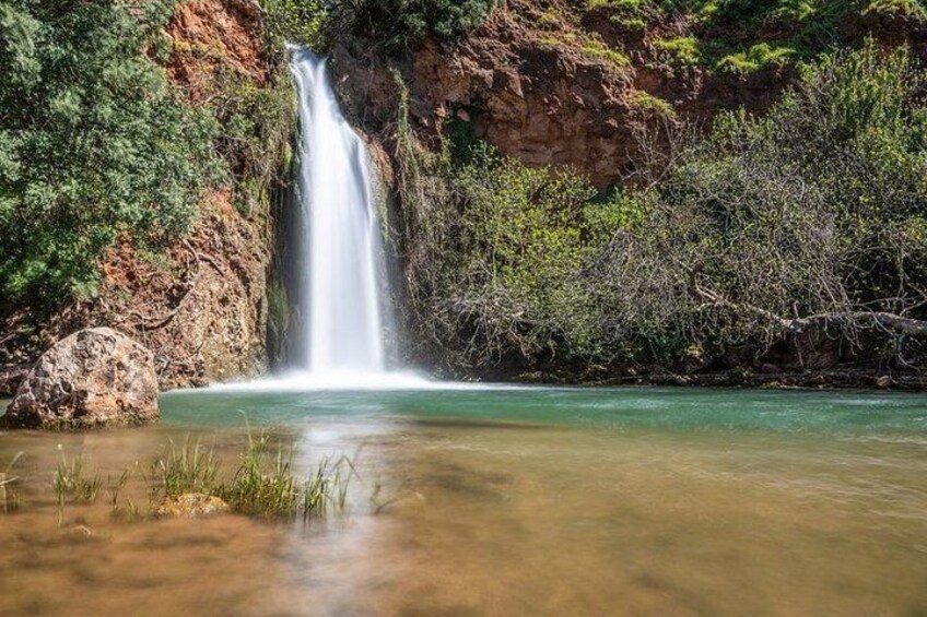 A waterfall, clear water, and surrounding greenery. 4