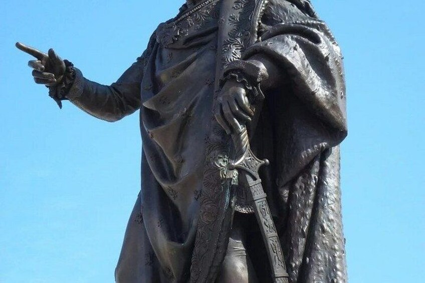A statue of a person in a robe pointing to the left. 2