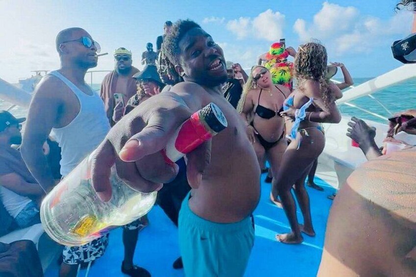 A group of people on a boat with a person holding a bottle. 5