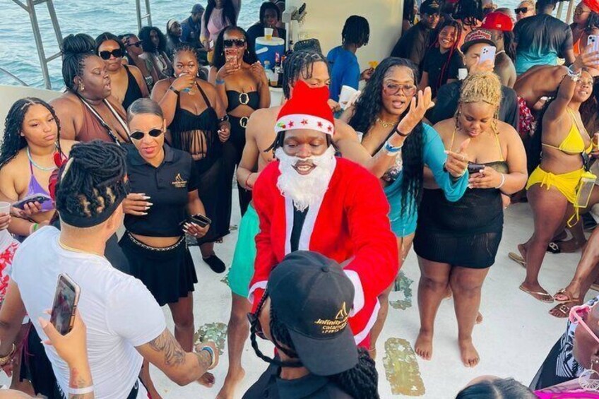 A group of people on a boat, some wearing festive attire, including a Santa Claus figure. 2